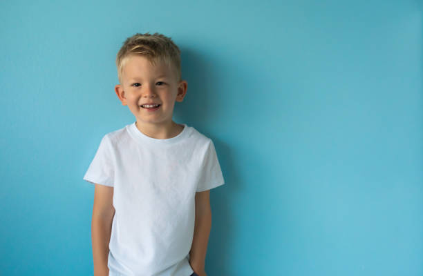 niño feliz de pie contra el fondo azul. - t shirt child white portrait fotografías e imágenes de stock