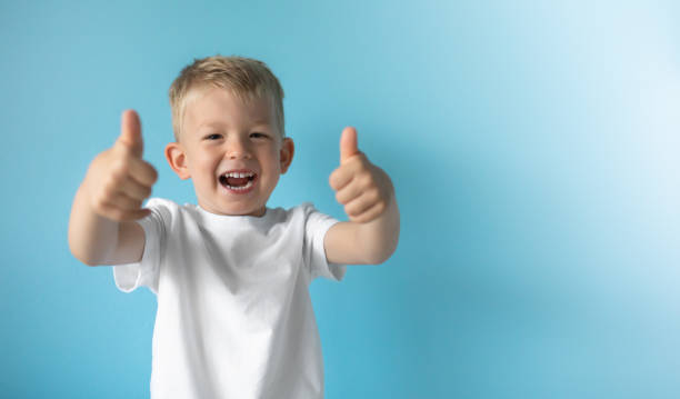 Happy excited little boy smiling with thumbs up.