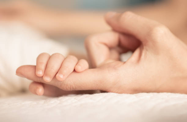 istock newborn baby's tiny small hand holding mothers finger. 1222468062