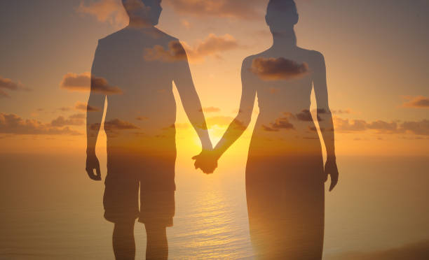 istock Man woman holding hands facing sunset. 1222468682