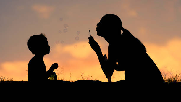 Mother and child playing blowing bubbles in the park.
