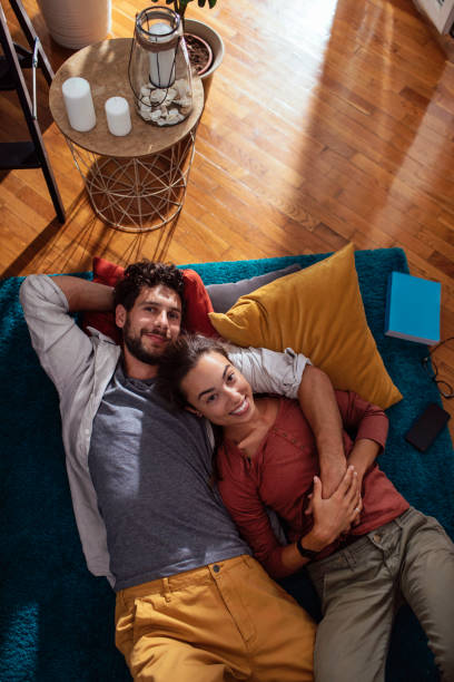 Every morning is special with you Young couple cuddling while lying down on their living room floor woman lying on the floor isolated stock pictures, royalty-free photos & images