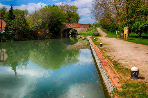 Peace and calm at the Basingstoke Canal, Hampshire, UK, landscape of the towpath, canal and old bridge. HDR image.