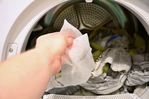 Put dryer sheet into a dryer Hand holding and put dryer sheet into a tumble clothes dryer. dryer stock pictures, royalty-free photos & images