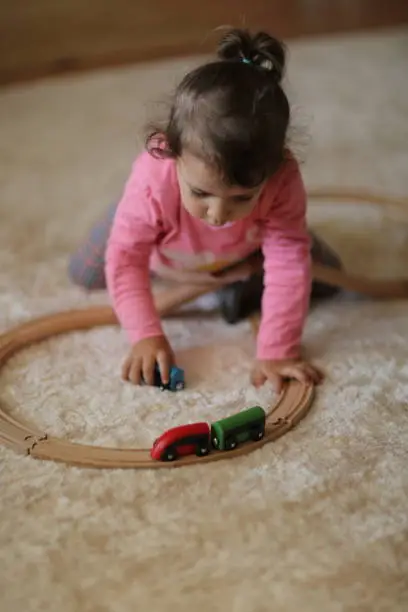 Photo of Cute little girl playing with wooden train