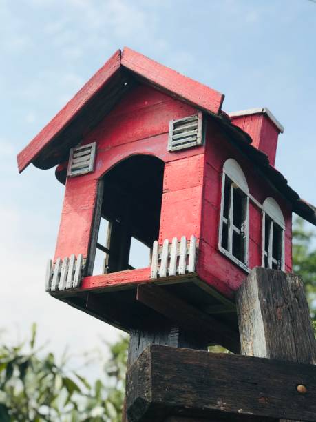 istock Red bird house, made from old wood, behind the sky, white clouds 1222479242