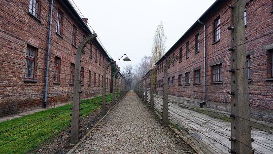 Oswiecim, Poland - May 12, 2016: Masonry blocks and fences with barbed wire in concentration camp Auschwitz-Birkenau in Oswiecim, Poland.