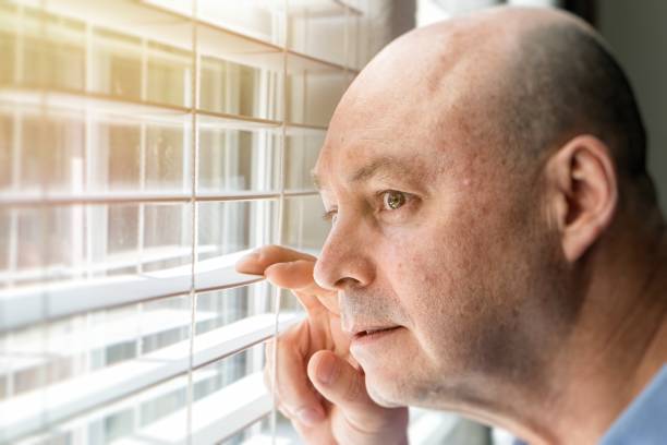 istock Mature man looking through a window inside his home locked down 1222482266