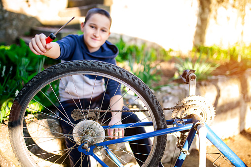 Little boy aged 11 repairing a bicycle at home in garden