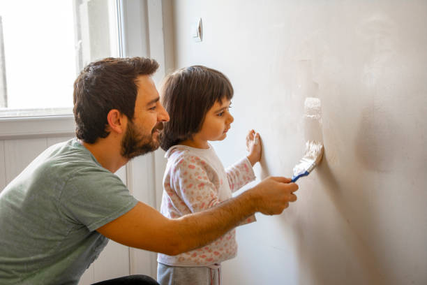 padre e sua figlia piccola dipingendo il muro - paintings child house childhood foto e immagini stock