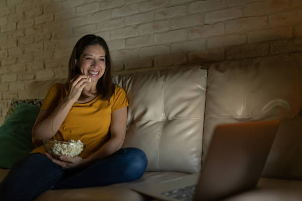 istock Woman laughing and watching a movie at night 1222496006