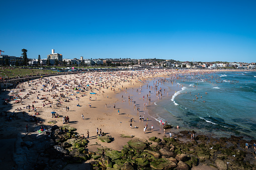 Thousands of people on Bondi Beach in the summertime enjoying the outdoors.