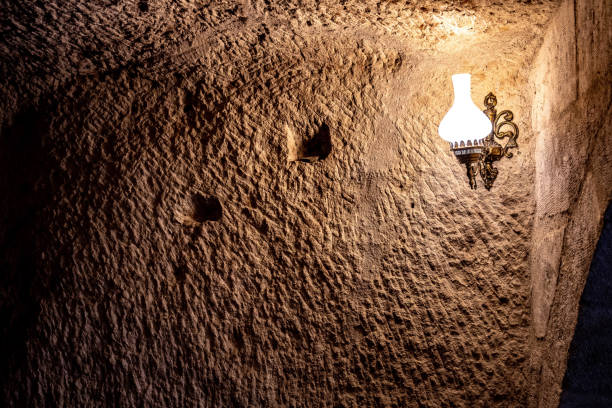Ancient rough wall in cave with light from lamp in darkness. Antique lamp on scratched surface of limestone wall in cave of Cappadocia Turkey. Grunge backdrop.