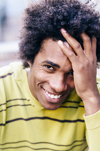 Cuban black tourist with afro hair sitting on the floor smiling to camera.