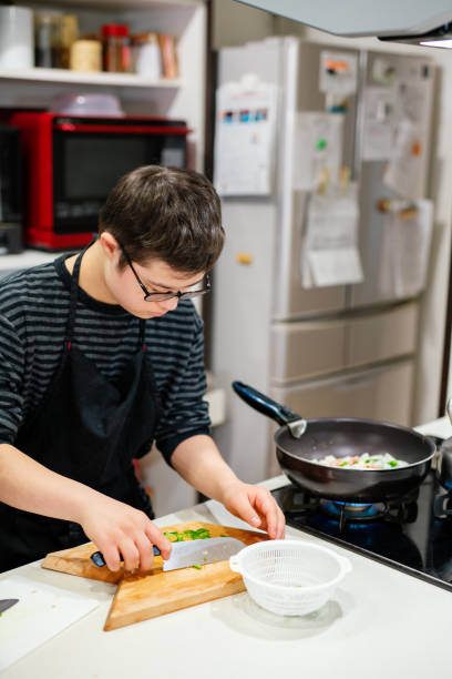 istock Teenage boy with Down's Syndrome preparing vegetable while cooking 1222518337