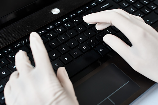 Hands in gloves typing on laptop keyboard. Virus protection concept