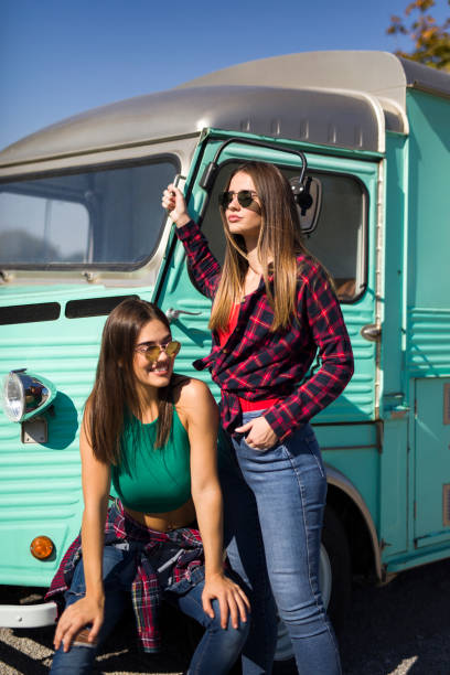 istock Smiling young women by the vintage minivan 1222520337