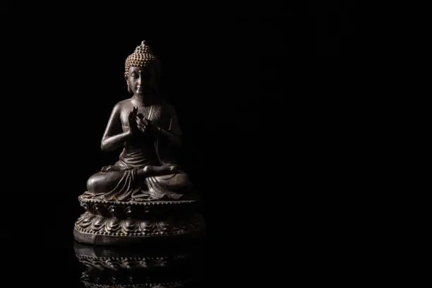 Statue of Buddha sitting in meditation With black copy space . Zen and meditation concept