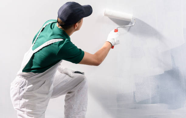 istock Male decorator painting a wall with white color. 1222526168
