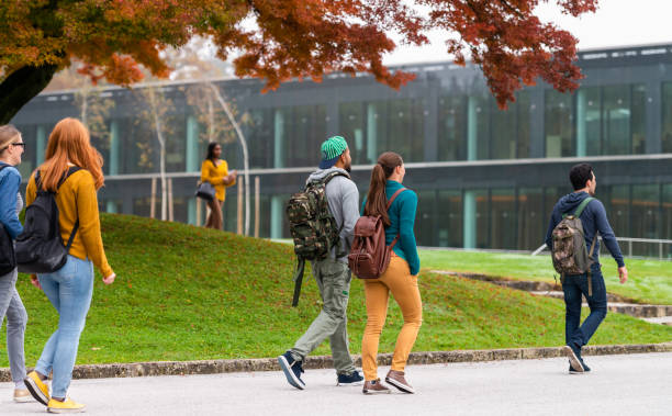 Students In Campus Group of students walking and standing in front of a modern glass university building campus stock pictures, royalty-free photos & images