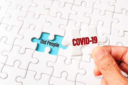 The COVID-19 word on white jigsaw puzzle go to replace old people word on blue gap - idea answer concept.