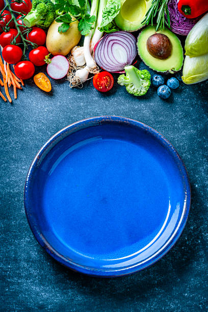 istock Vegan food: empty blue plate and healthy fresh vegetables border. Copy space 1222530910