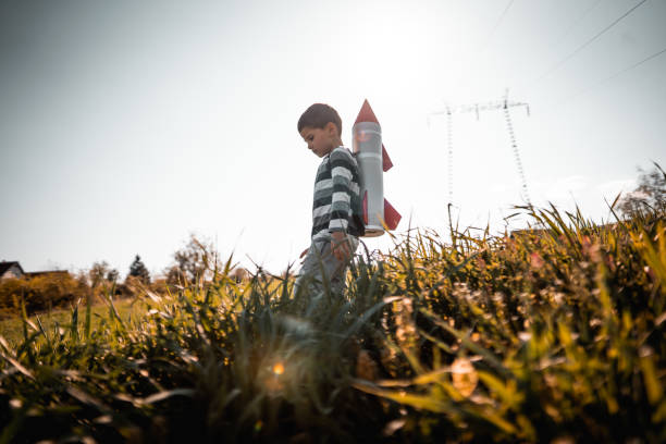 自家製ジェットパックで草原で遊ぶ小さな男の子 - superhero child creativity little boys ストックフォトと画像