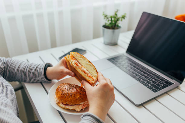 donna che lavora su laptop mentre pranza - sandwich turkey lunch table foto e immagini stock