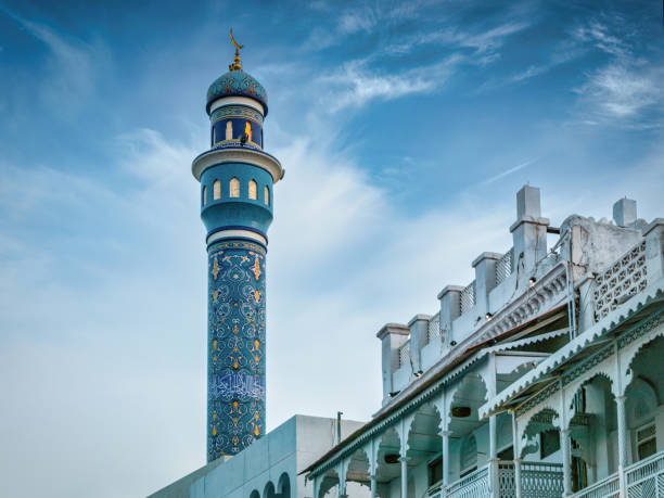 A high minaret with wooden ornament of a mosque against blue cloudy sky, minaret or tower aspiring to heaven, Islamic religion and architecture concept,  a mosque pillar pole, selective focus