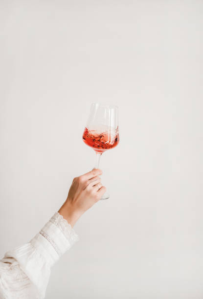femme de main retenant et tournant le verre du vin rose - champagne champagne flute pouring wine photos et images de collection