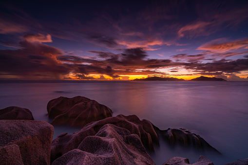 long exposure shot of beautiful sunset mood with colorful sky on tropical island granite rocks in foreground