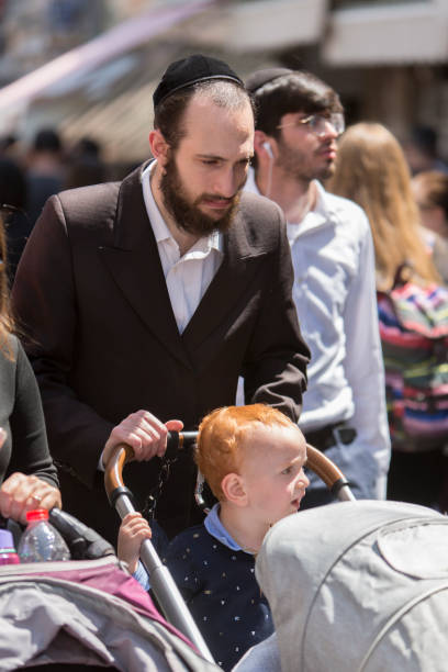 père poussant la poussette de chéri avec son fils rouge dans la vieille ville de jérusalem, israel - hasidism photos et images de collection