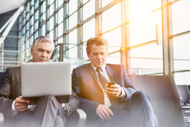 Mature businessman waiting for boarding in airport Mature businessman waiting for boarding in airport newspaper airport reading business person stock pictures, royalty-free photos & images