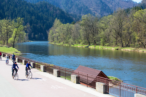 Szczawnica, Poland - April 20, 2019: Dunajec River Gorge, bike path on the banks of the river. Unknown people riding bicycles