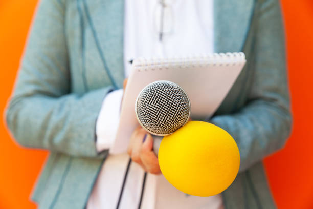 istock Female reporter at press conference or media event, writing notes, holding microphone. Journalism concept. 1222541177