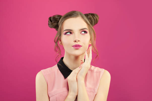 istock Young woman looking up aside and smiling on bright pink background 1222543909
