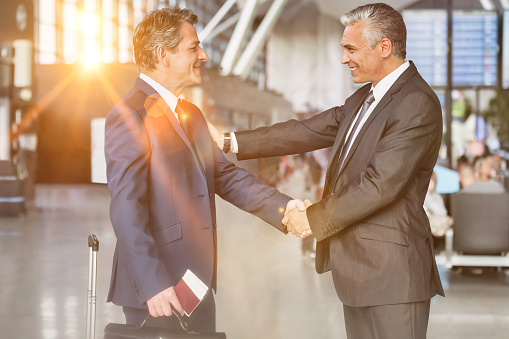 Mature businessman shaking hands with business partner in airport
