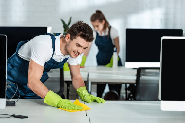 istock two young cleaners wiping desks with rags in office 1222545474
