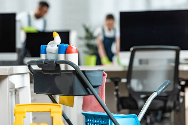selective focus of cart with cleaning supplies and two cleaners on background stock photo