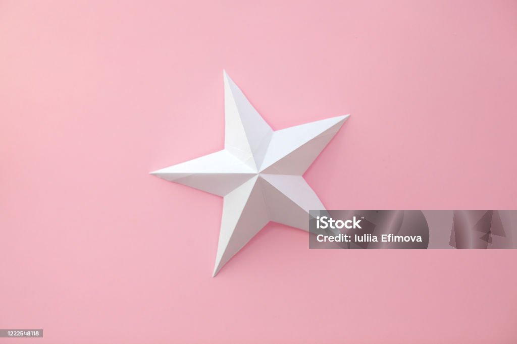 Paper art star. Handmade paper art and cut white star on pink background. Star Shape Stock Photo