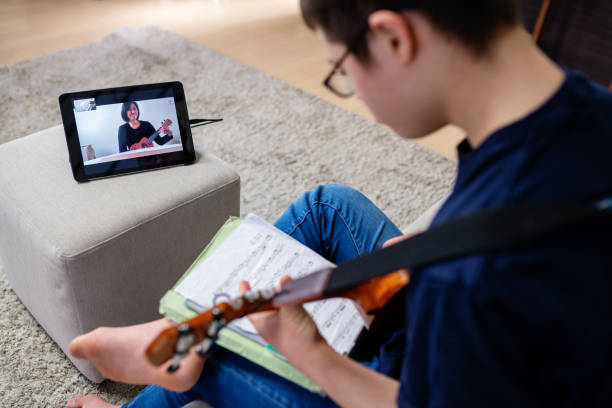 다운 증후군을 가진 십대 소년은 인터넷을 통해 집에서 먼 학습 음악 수업을 복용 - guitar child music learning 뉴스 사진 이미지