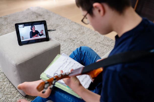 nastoletni chłopiec z zespołem downa biorąc odległe lekcje muzyki w domu przez internet - guitar child music learning zdjęcia i obrazy z banku zdjęć