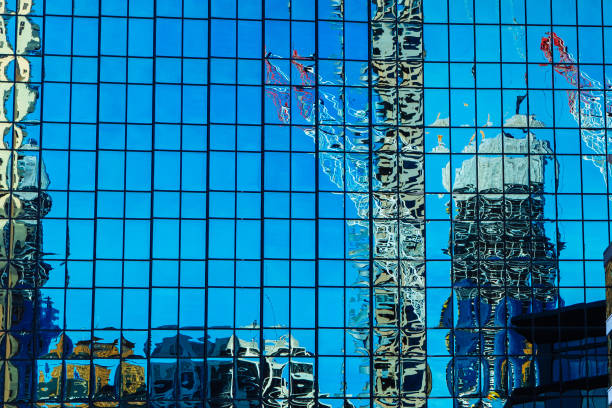Corporate building facade with reflections on the side of the building of cranes and other construction activities.