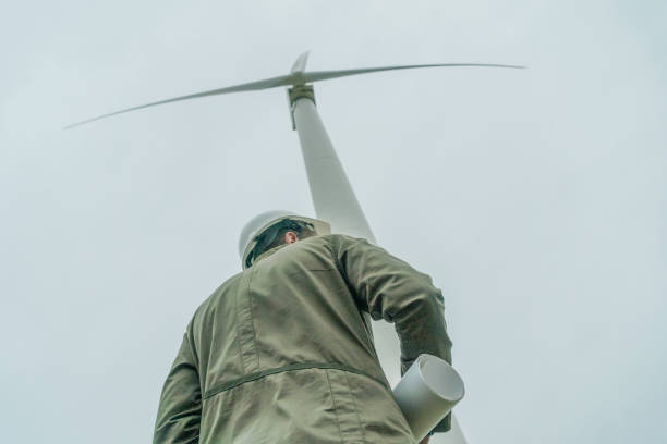 istock engineer examines the place with a plan in his hands. Project Manager at the wind farm. photo from the back 1222557130