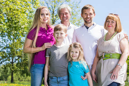 Multigeneration family portrait outdoors. Happy parents with two children and grandparents in summer park