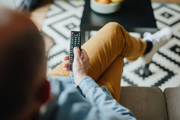 uomo anziano che guarda la tv a casa - fare zapping foto e immagini stock