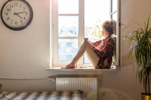 Young woman looking out of window Beautiful young woman sitting at a window sill having rest avoidance photos stock pictures, royalty-free photos & images