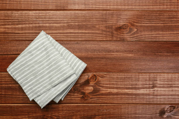 istock Top view on a dark wooden table with a linen kitchen towel or textile napkin. a tablecloth on a countertop made of old wood. Copy space for text. 1222561723