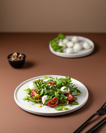 Green salad with tomato in modern style on beige background. Healthy food