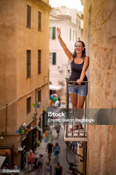 A Tourist Woman Waving Her Hand At The Balcony Of An Historical Building Stock Photo - Download Image Now